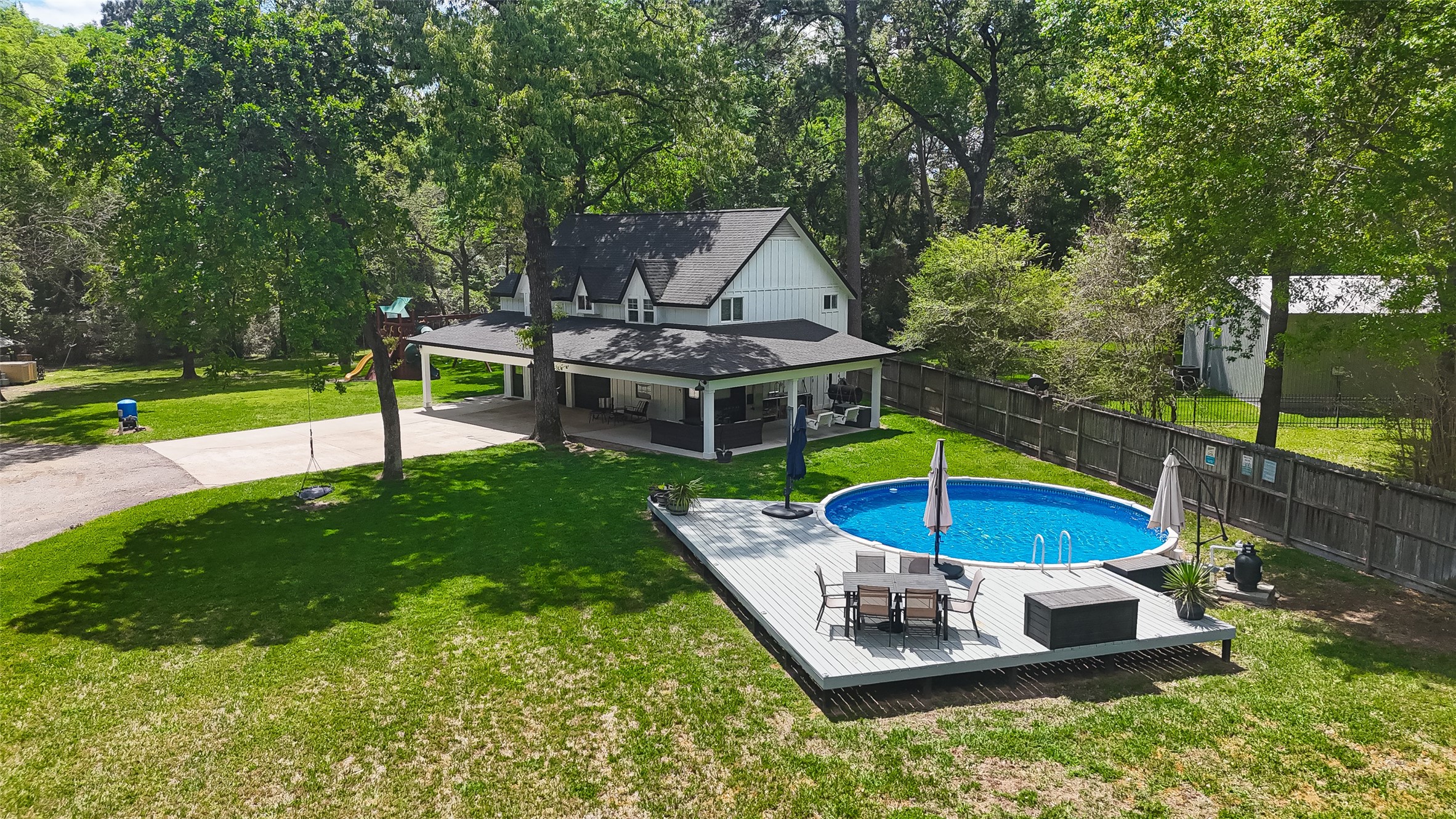 819 Sentinel Oaks Pinehurst, TX 77362 - Photo 4 of 38 Charming home with a spacious backyard, featuring a covered patio and a round above-ground pool with a surrounding deck. The property is bordered by mature trees and a wooden fence, offering privacy and a serene atmosphere. Perfect for outdoor entertaining and relaxation.