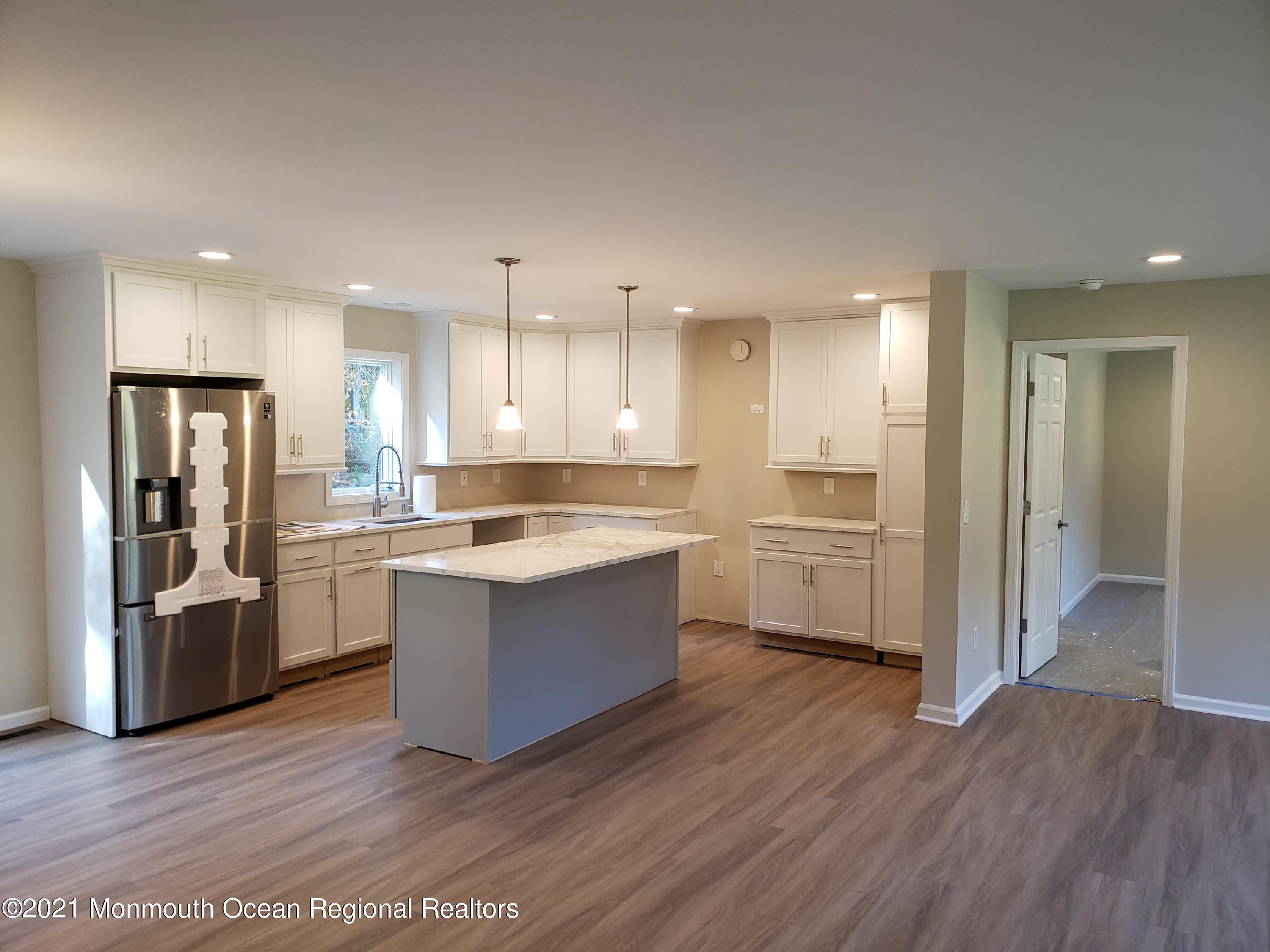 154 Jackson Mills Road Freehold, NJ 07728 - Photo 7 of 19 a large kitchen with a center island wooden floor stainless steel appliances and a window