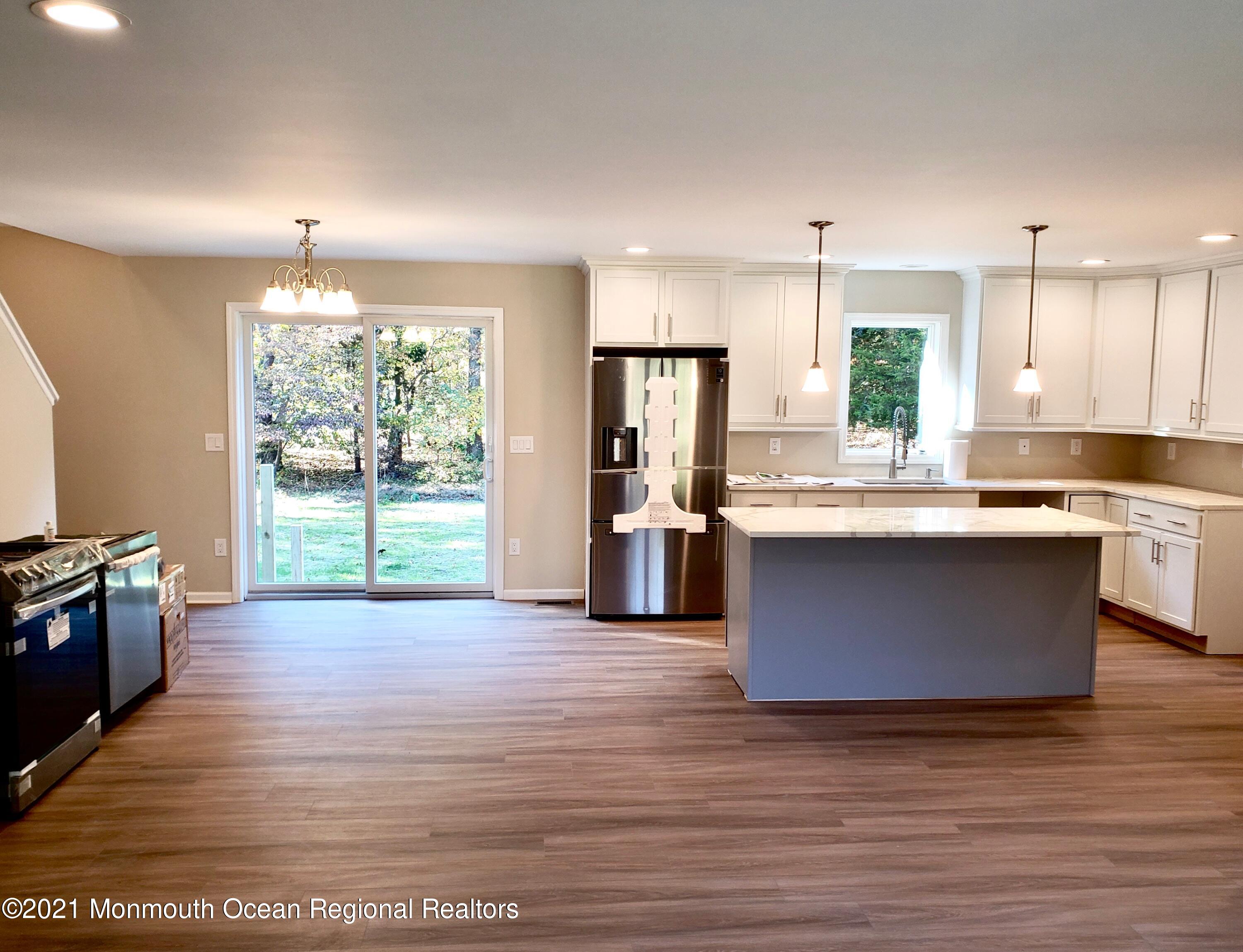 154 Jackson Mills Road Freehold, NJ 07728 - Photo 10 of 19 a large kitchen with stainless steel appliances granite countertop a stove a sink dishwasher a refrigerator and a dining table with wooden floor
