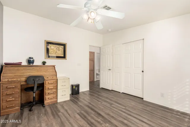 a view of a livingroom with a fireplace a ceiling fan and wooden floor