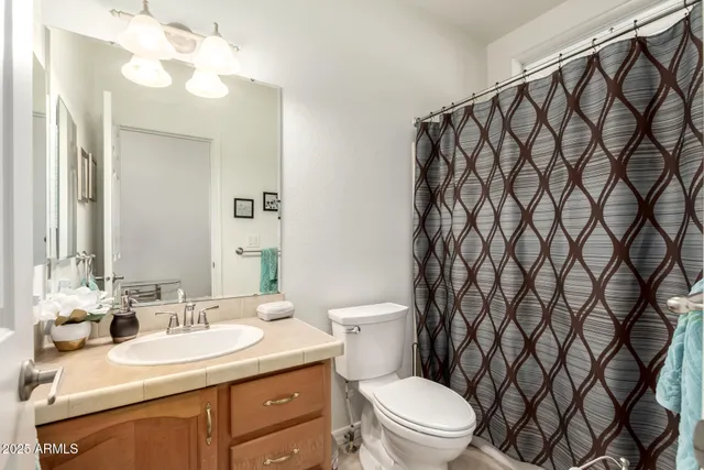 a bathroom with a granite countertop sink and a toilet
