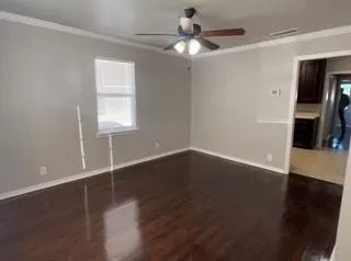 an empty room with wooden floor fan and windows