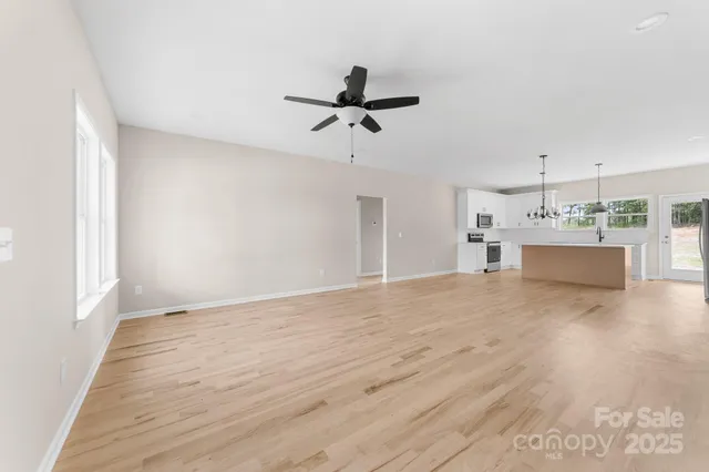 a view of a livingroom with a ceiling fan wooden floor and a ceiling fan
