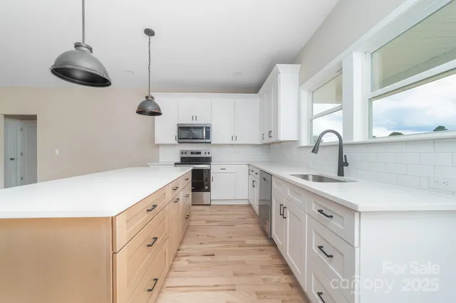 a kitchen with stainless steel appliances a sink a stove and a wooden floors
