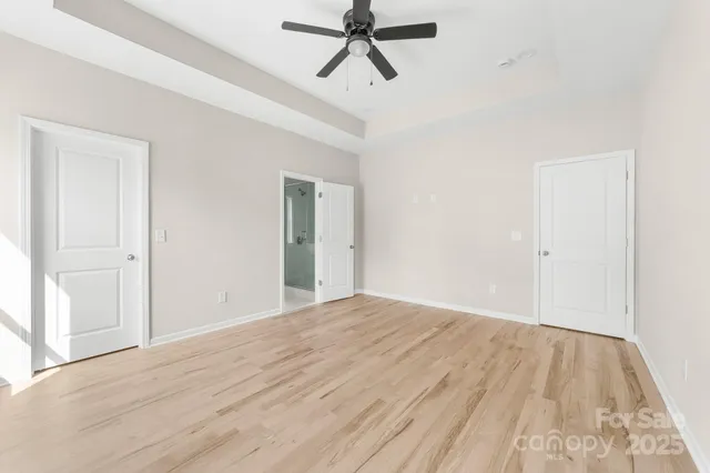 a view of empty room with wooden floor and ceiling fan