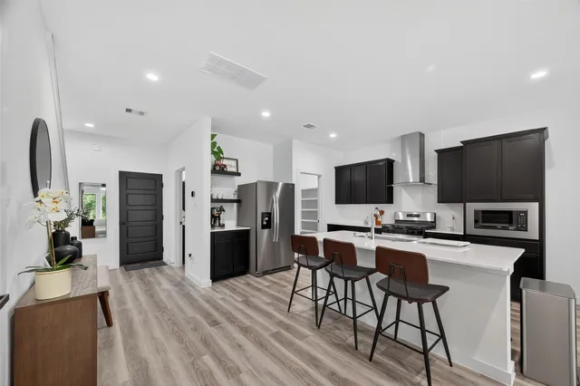 a living room with furniture a flat screen tv and a refrigerator