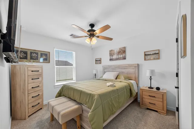 a bedroom with a bed flat screen tv and a large window