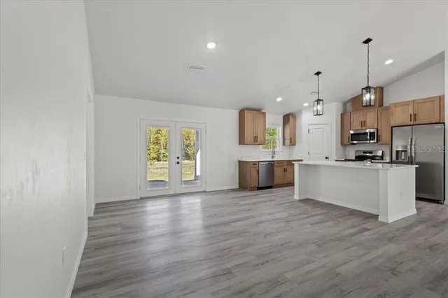 a large kitchen with cabinets wooden floor and stainless steel appliances
