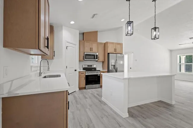 a large kitchen with stainless steel appliances a large counter top a sink a stove and refrigerator