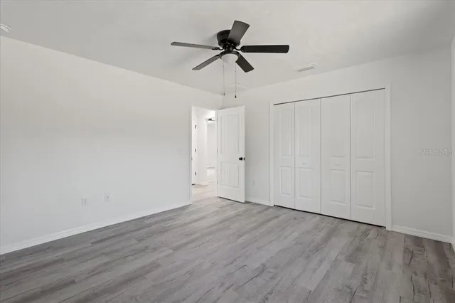 a view of empty room with wooden floor and ceiling fan