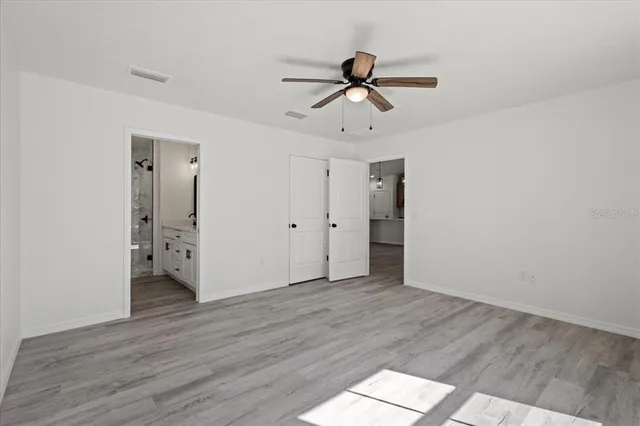 a view of empty room with wooden floor and ceiling fan