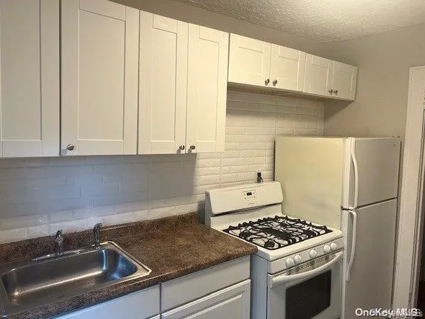 a kitchen with granite countertop a sink stove and refrigerator