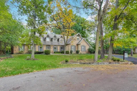 a view of house with a big yard and large trees