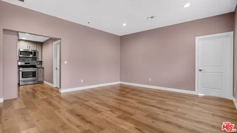 a view of an empty room with wooden floor and a window