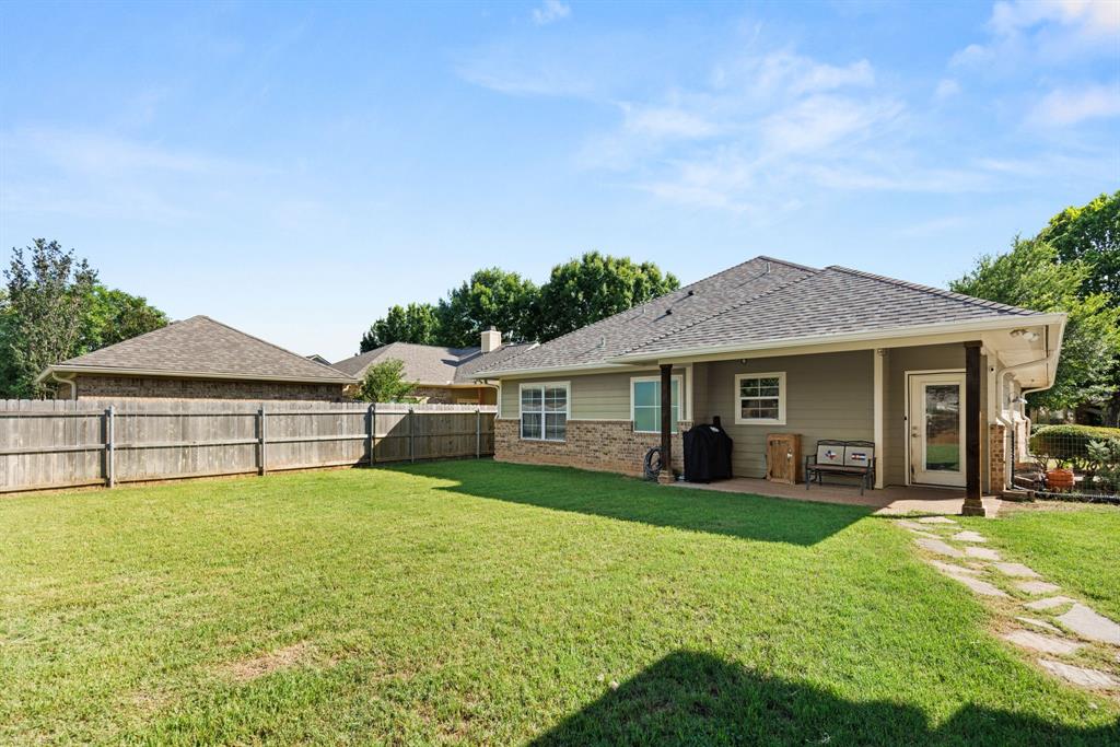 10609 Aquilla Trail Waco, TX 76708 - Photo 11 of 30 Expansive backyard featuring a manicured lawn, full privacy fencing, a covered patio, and a stone walkway