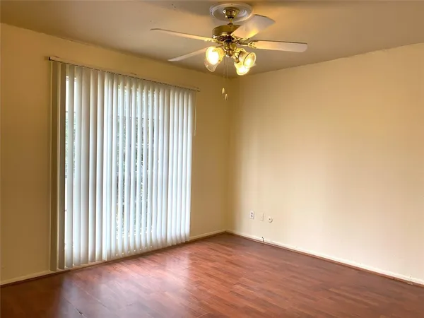 an empty room with wooden floor fan and windows