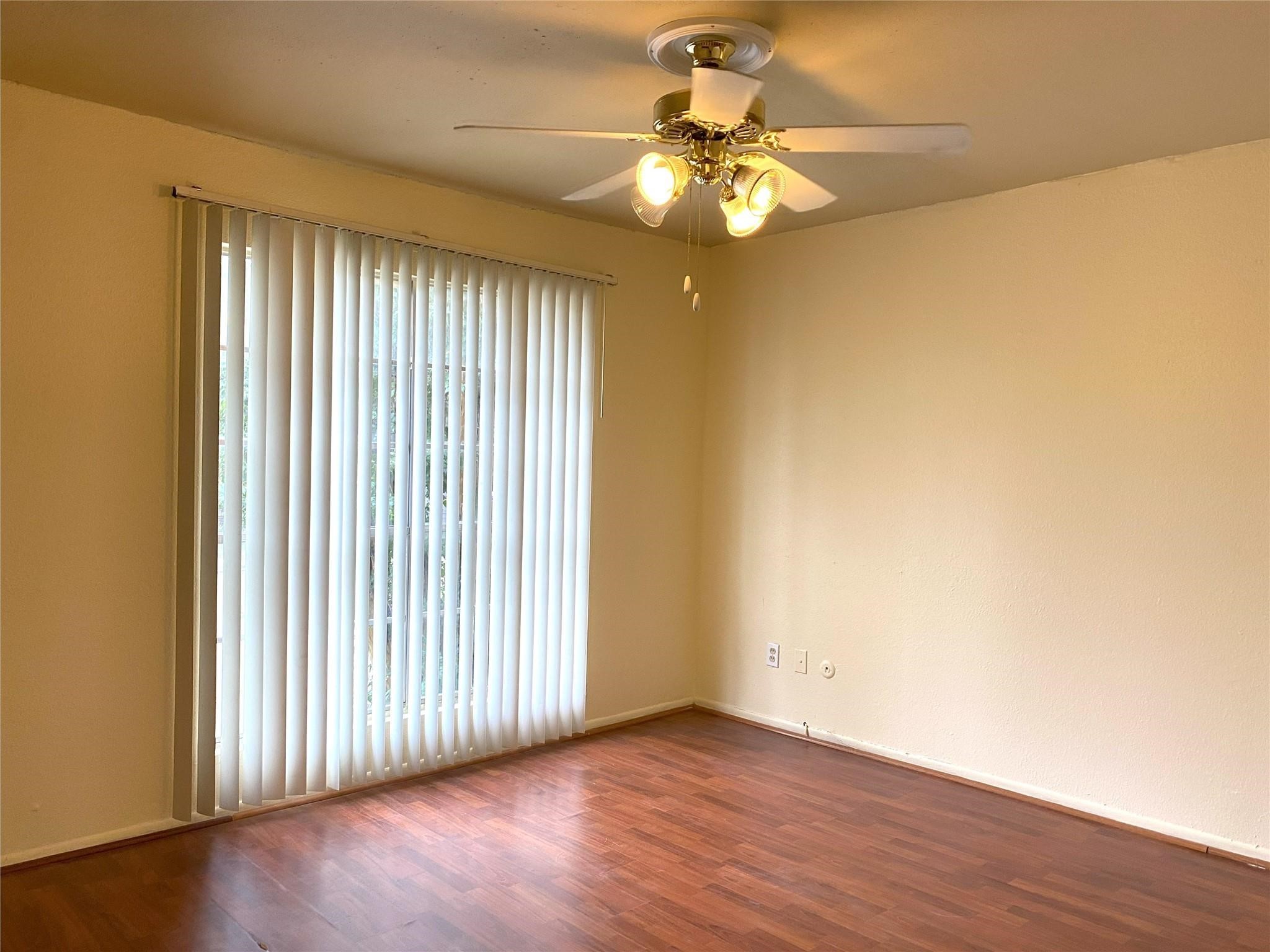 7831 Fuqua Street, Unit 7831 Houston, TX 77075 - Photo 5 of 15 an empty room with wooden floor chandelier fan and windows