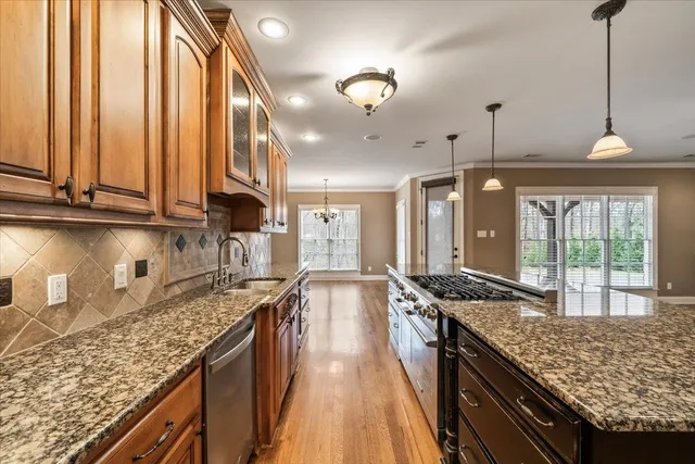 a kitchen with stainless steel appliances granite countertop a sink a stove and a refrigerator