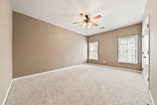 an empty room with windows and ceiling fan