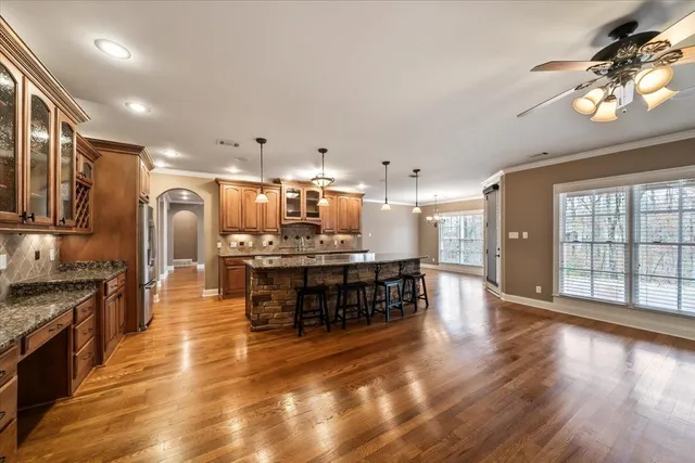 a kitchen with stainless steel appliances granite countertop a stove top oven a sink a dining table and chairs with wooden floor