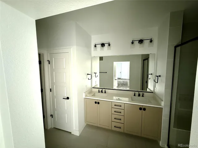 a bathroom with a double vanity sink a mirror a shower and a mirror