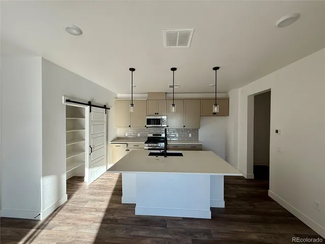 a kitchen view with wooden floor and a view of living room