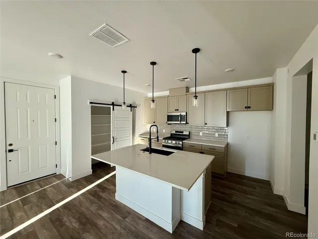 a kitchen with kitchen island a stove a refrigerator and a sink