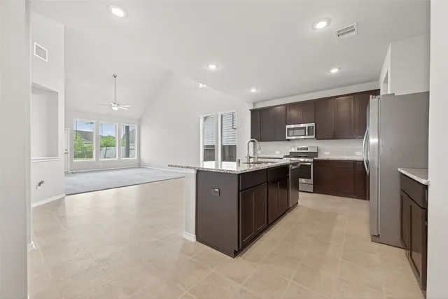 a large kitchen with kitchen island a large counter top space a sink stainless steel appliances and cabinets