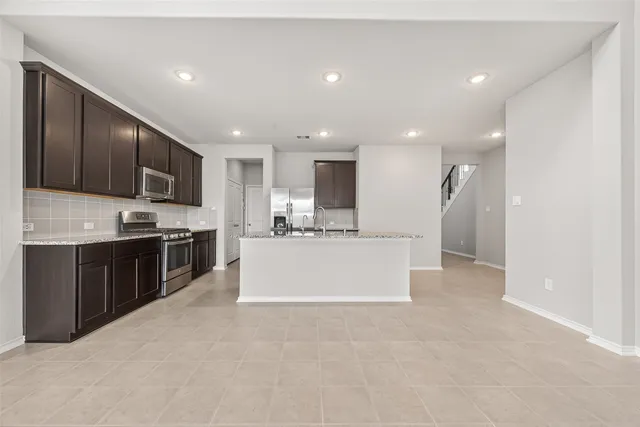 a large kitchen with stainless steel appliances kitchen island a large counter top and a stove top oven