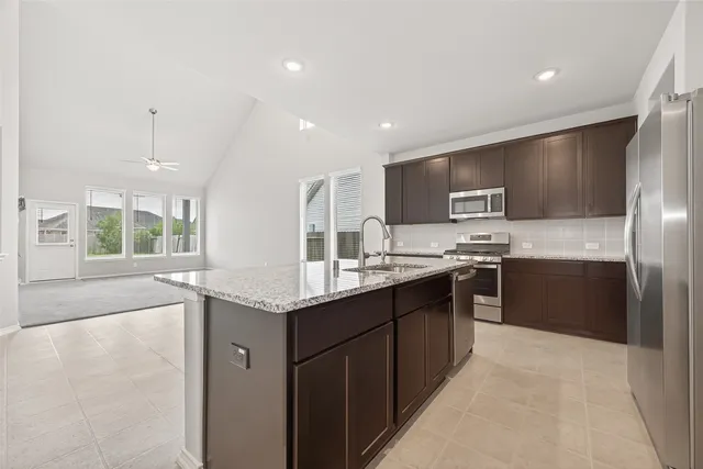 a kitchen with stainless steel appliances granite countertop a sink stove and refrigerator