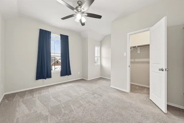 a view of an empty room with chandelier fan