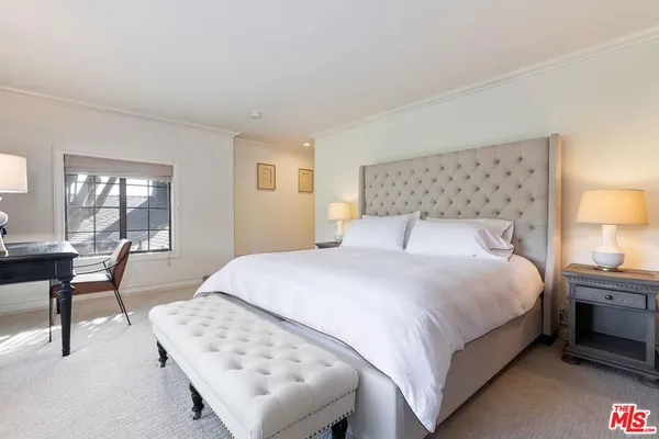 a bedroom with a bed table chair and a window