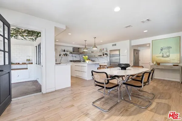 a dining hall with stainless steel appliances kitchen island granite countertop a dining table chairs and view living room