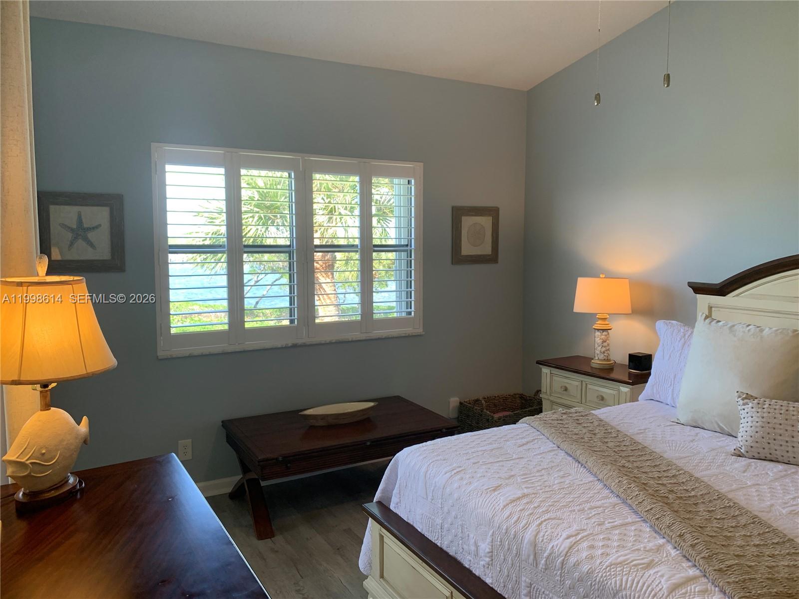 6082 Southeast Landing Way, Unit 10 Stuart, FL 34997 - Photo 18 of 35 a bedroom with a bed and wooden floor