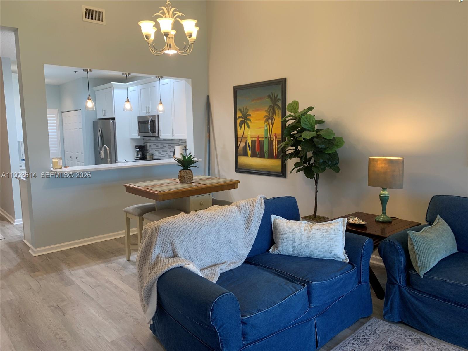 6082 Southeast Landing Way, Unit 10 Stuart, FL 34997 - Photo 23 of 35 a living room with furniture a chandelier and a dining room