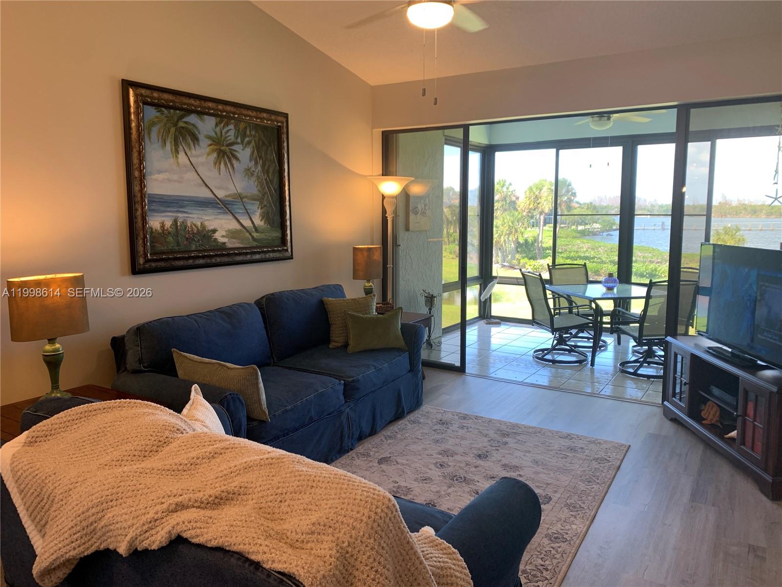 6082 Southeast Landing Way, Unit 10 Stuart, FL 34997 - Photo 24 of 35 a bedroom with a balcony a large bed and a couch