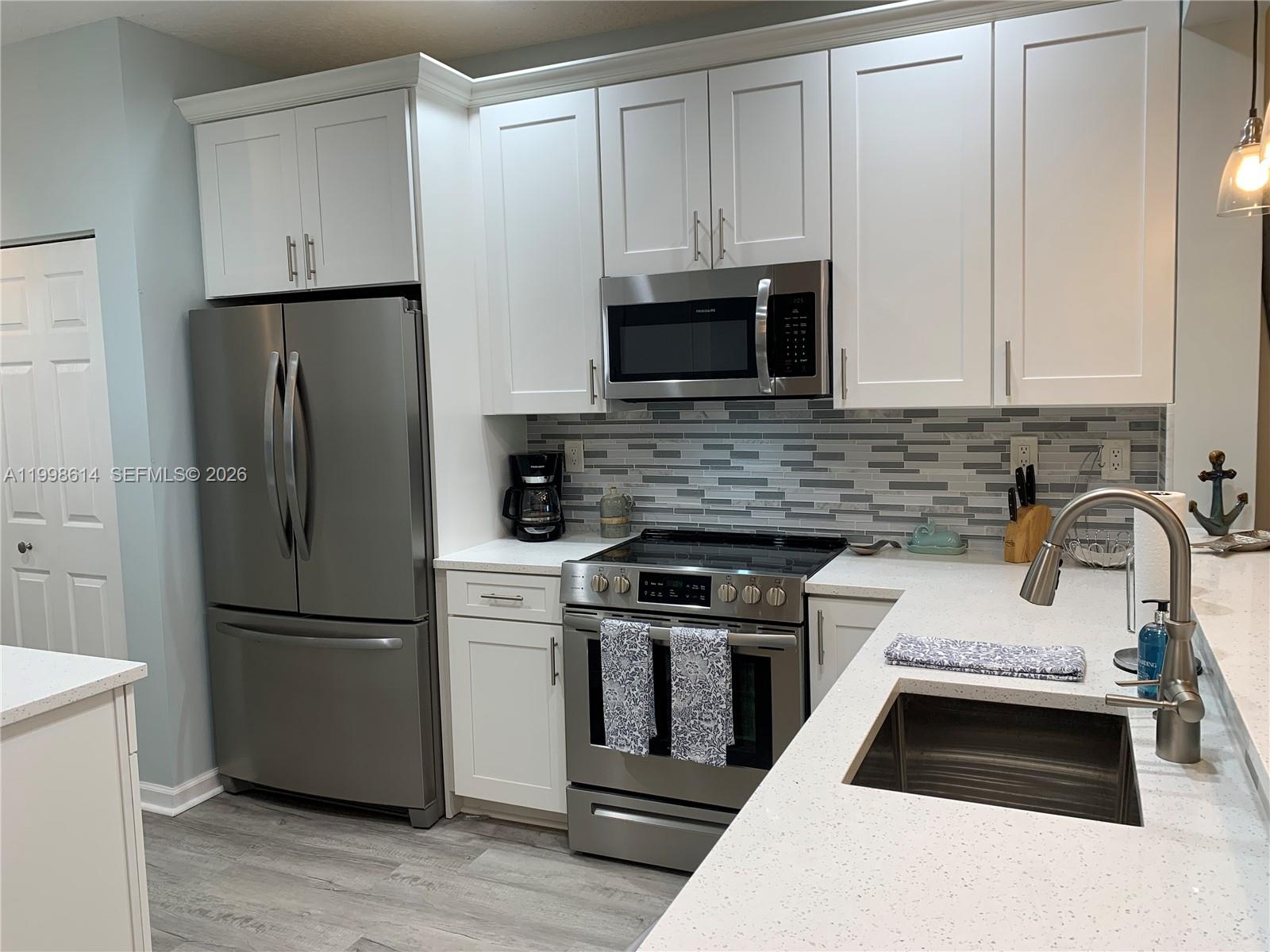 6082 Southeast Landing Way, Unit 10 Stuart, FL 34997 - Photo 7 of 35 a kitchen with granite countertop a refrigerator stove and sink