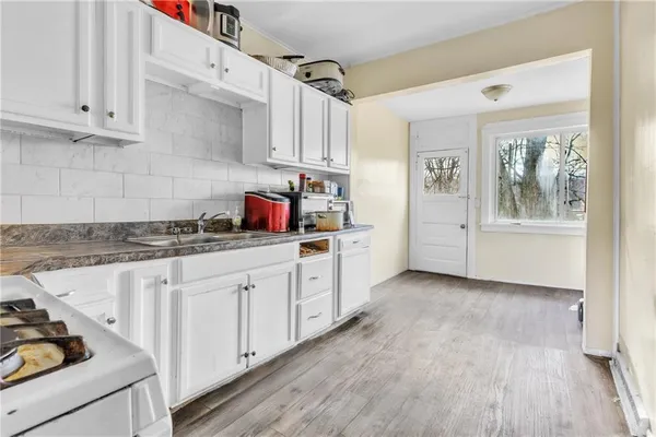 a kitchen with stainless steel appliances granite countertop a stove a sink and white cabinets
