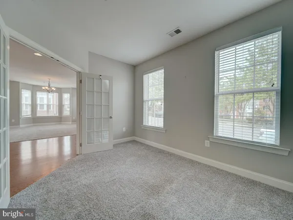an empty room with wooden floor ceiling fan and windows