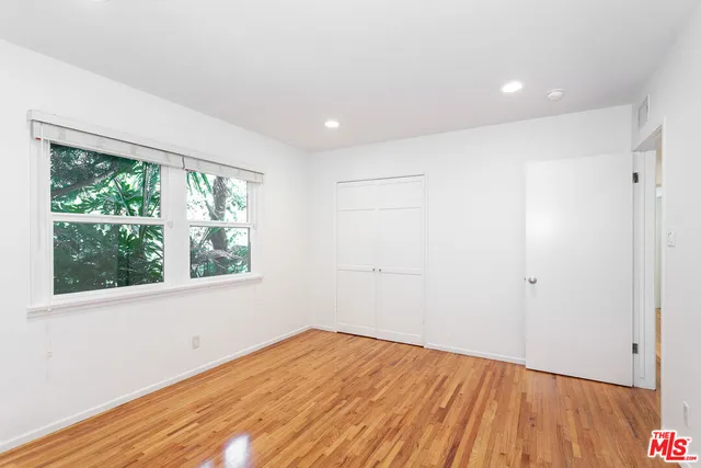 a view of empty room with wooden floor and fan