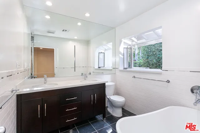 a bathroom with a double vanity sink toilet and a mirror