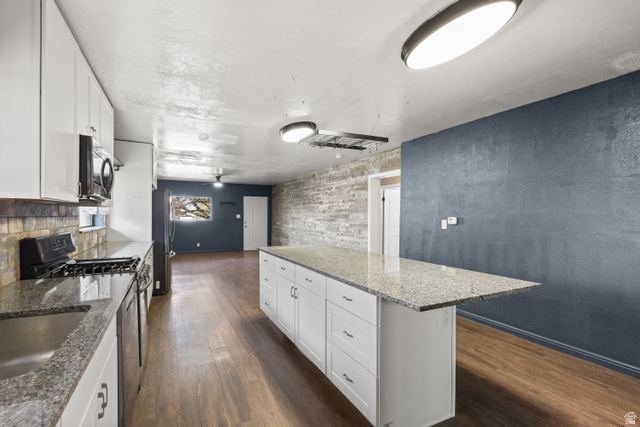 2576 Gramercy Avenue Ogden, UT 84401 - Photo 8 of 20 Kitchen featuring white cabinetry, dark stone countertops, dark wood-style flooring, a kitchen island, and stainless steel appliances