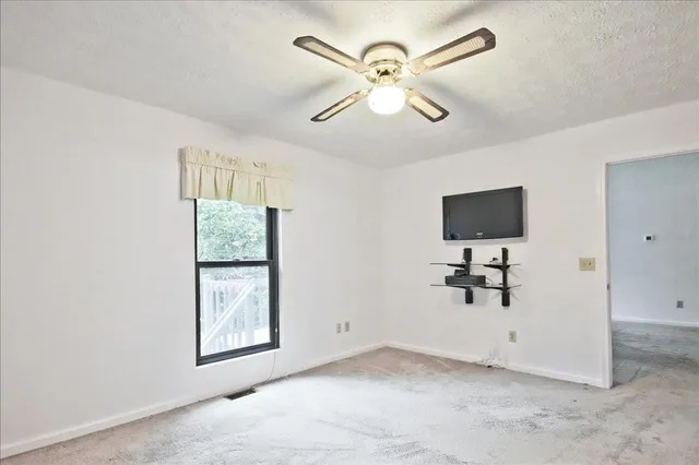 an empty room with windows and fan