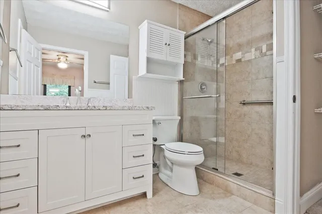 a bathroom with a granite countertop sink toilet and mirror