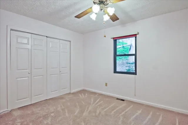 an empty room with closet and a chandelier fan