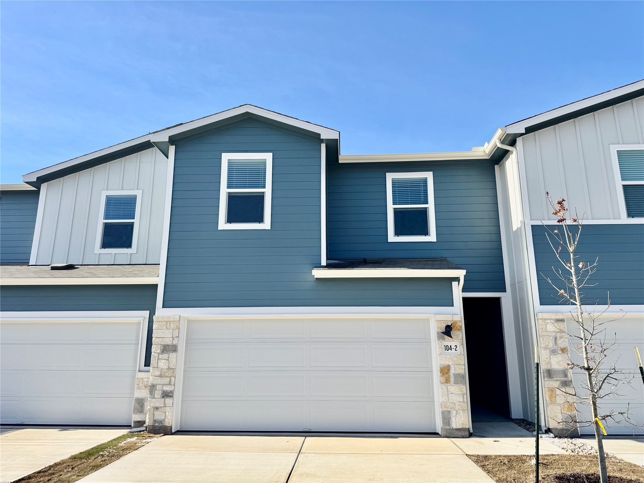 View of front of property featuring board and batten siding, stone siding, and driveway