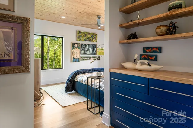 a bedroom with a bed wooden floor and large window