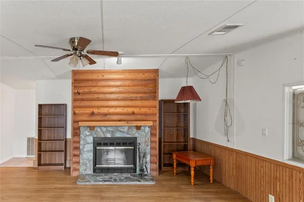 an empty room with wooden floor chandelier fan and windows