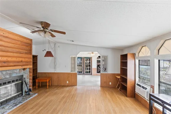 an empty room with wooden floor fan and windows
