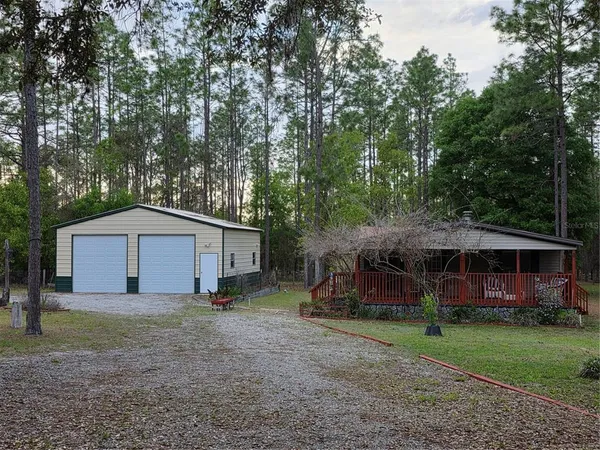 a view of a house with a yard and large trees